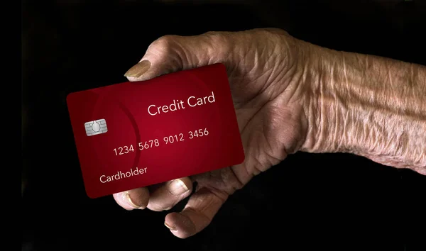 An elderly hand holds a credit card to illustrate the theme: Which credit card is best for older men and women. This is an illustration.
