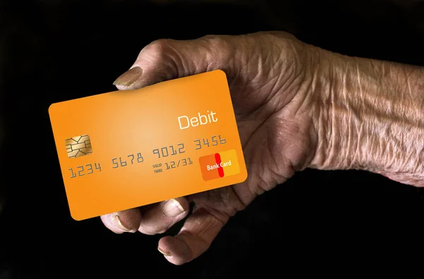 An elderly hand holds a debit card to.