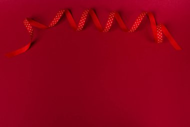 Dalgalı polka dot kırmızı kurdele kırmızı zemin üzerine. Tatil ya da dekorasyon konsepti, düz lay, ana sayfa görünümü. Kopya alanı tasarım veya metin için.