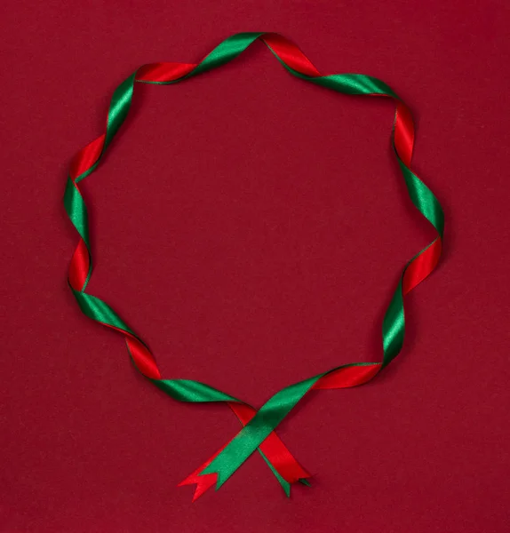 Christmas round frame of wavy ribbons on red background. — Stock Photo, Image