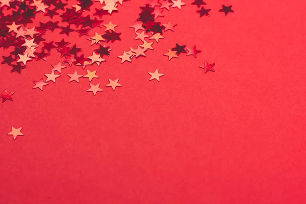 Metallic confetti on festive red paper background.