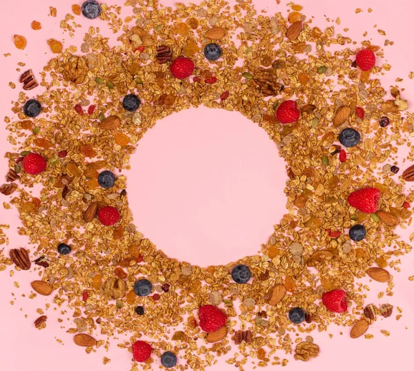 Dağınık granola, fındık ve pembe bir arka plan üzerinde çilek.