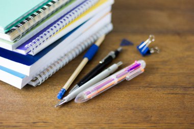 Notebads ve kalemler üzerinde ahşap masa yığını.