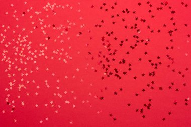 Metallic star shaped confetti on festive red background. clipart
