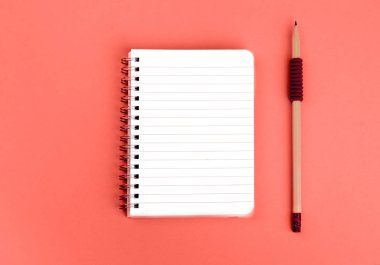 Spiral Not defteri ve kalem mercan arka plan üzerinde.