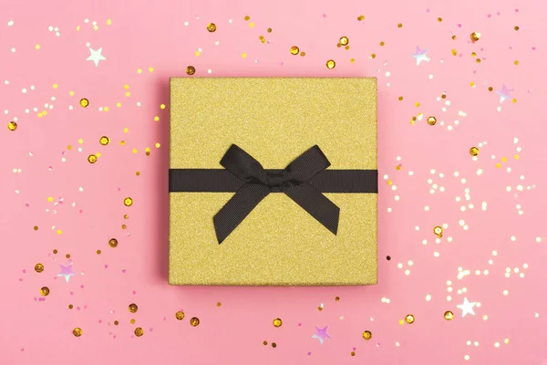 Geschenkdoos met strik op roze achtergrond met confetti. — Stockfoto