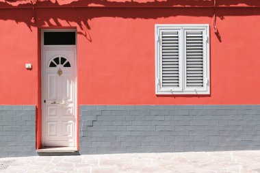 Beyaz ahşap kapı ve gri tuğla ile mercan duvar beyaz pencere.