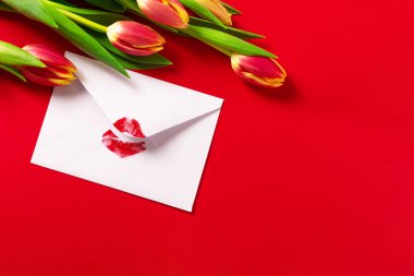 Sevgililer Günü geçmişi. Kırmızı rujlu öpücük ve kırmızı laleli zarf..