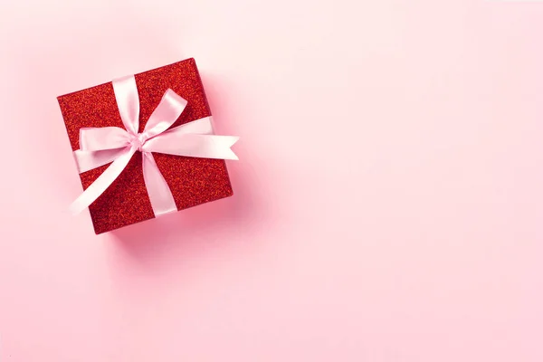 Rode geschenkdoos met roze lint op roze achtergrond. — Stockfoto