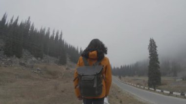 Uzun saçlı bir adam dağlardaki bir borunun içinden geçiyor.