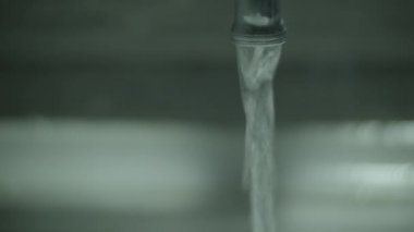 Banyodaki musluktan su dökülüyor.