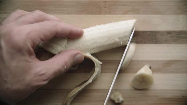 Schneiden einer Banane auf einem Schneidebrett — Stockvideo