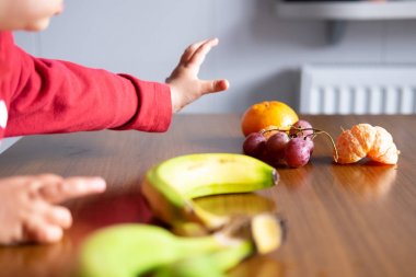 Bebek el ahşap bir masada farklı meyveler manipüle