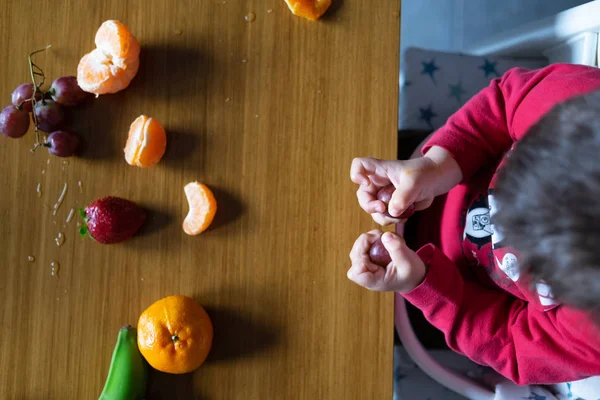 Baby s hand manipulating different fruits on a wooden table — Stock Photo, Image