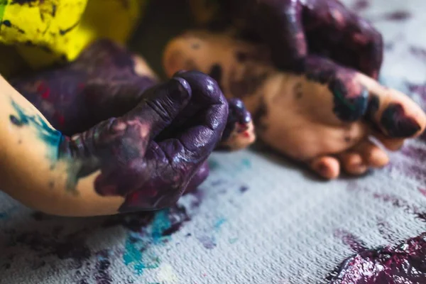 Pequeño niño manos y pies cubiertos de múltiples colores — Foto de Stock