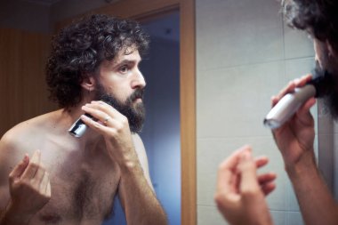 Orta yaşlı İspanyol adam sakalını kesiyor.