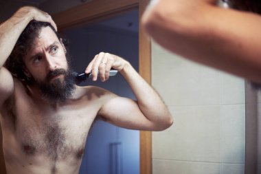 Orta yaşlı İspanyol adam sakalını kesiyor.