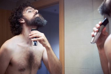 Orta yaşlı İspanyol adam sakalını kesiyor.