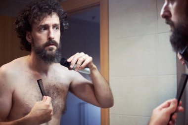 Orta yaşlı İspanyol adam sakalını kesiyor.