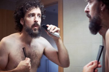 Orta yaşlı İspanyol adam sakalını kesiyor.