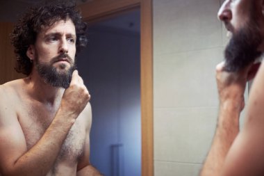 Orta yaşlı İspanyol adam sakalını kesiyor.