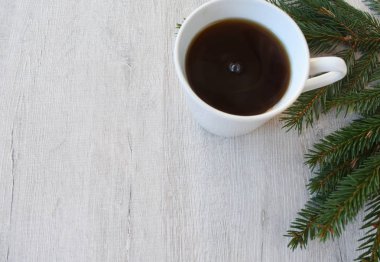 Arka plan dokusal kurulu. Köknar dalı yanındaki bir içkiyle beyaz Kupası.