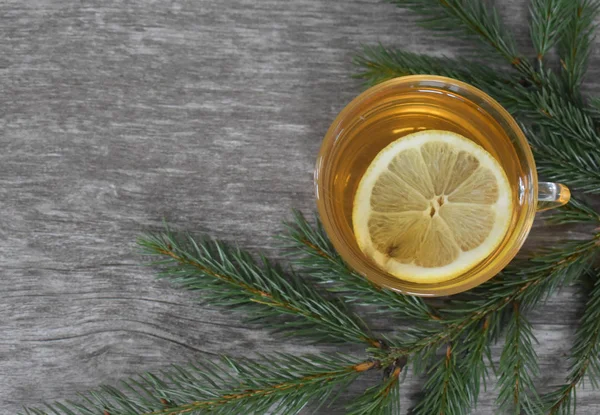 Drink with lemon on the background of a textured Board and fir twigs.