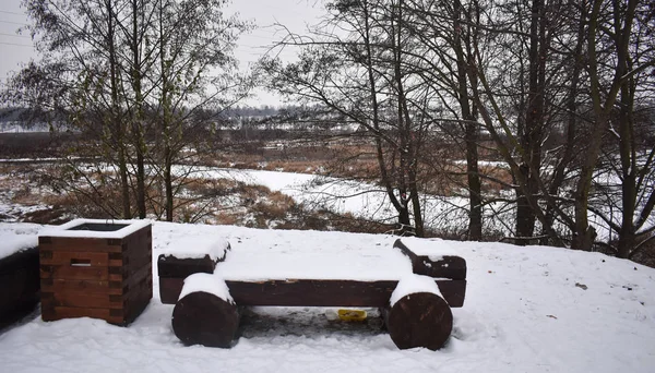 Vacation spot. snow-covered bench on the background of trees.