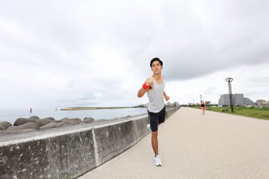 Genç adam deniz kenarında koşu