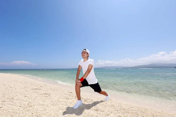 アジア人の男性がビーチでストレッチ — ストック写真