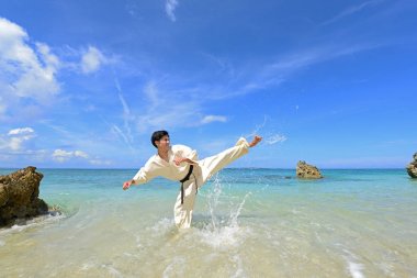 Genç adam sahilde karate çalışıyor.