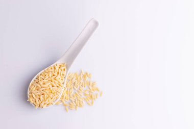 Beyaz seramik kaşıkta Orzo makarna, beyaz arka plan üzerinde izole. 