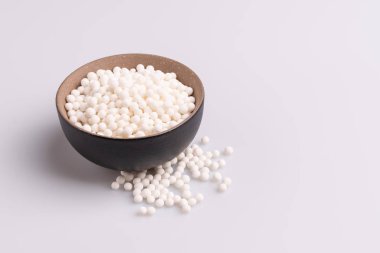 Tapyoka inci veya kahverengi bir kapta sagu tohumu, beyaz arka plan üzerinde izole