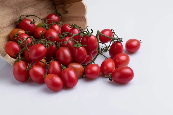 Pile of red grape tomatoes in wooden bowl, isolated on white background