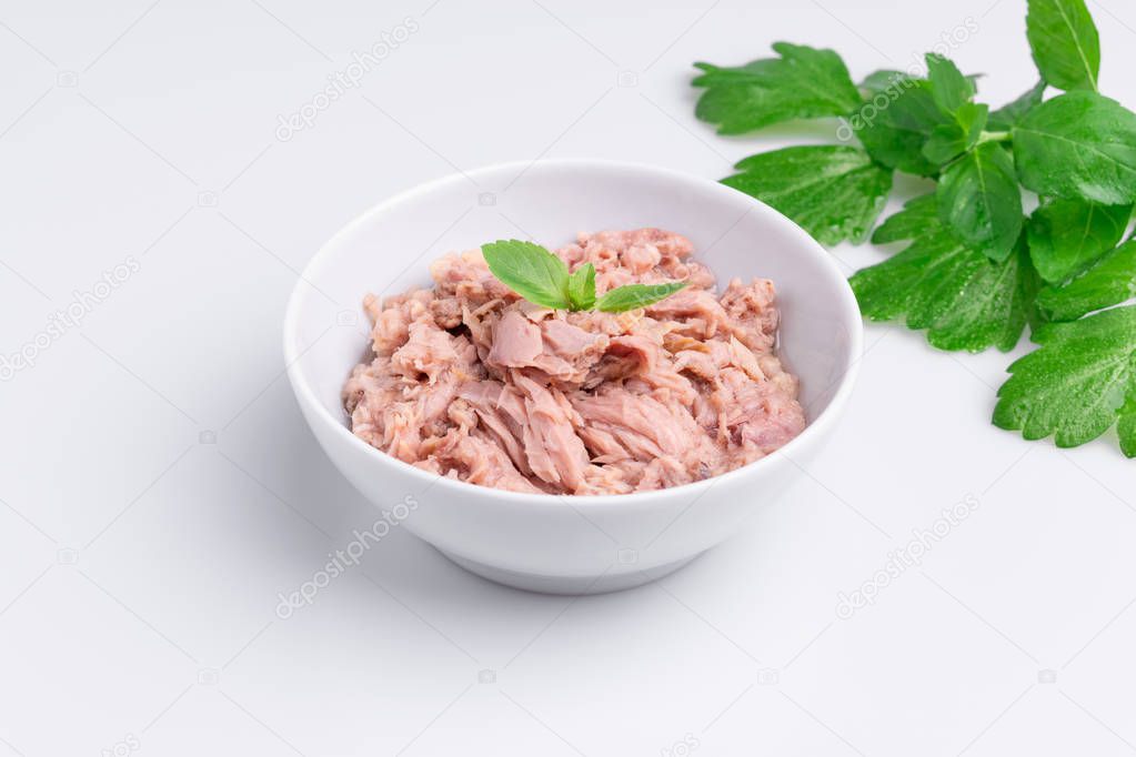 Canned tuna in a white bowl, isolated on white background, angle view
