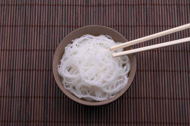 Pişmiş pirinç erişte ahşap arka plan üzerinde izole çubukları ile kase Tay tarzı.