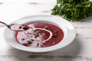 Beyaz ahşap masa arka planda beyaz bir tabakta ekşi krema ile lezzetli pancar çorbası