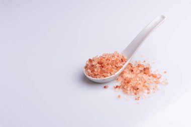 Beyaz arka plan üzerinde beyaz bir kaşık pembe himalaya tuzu