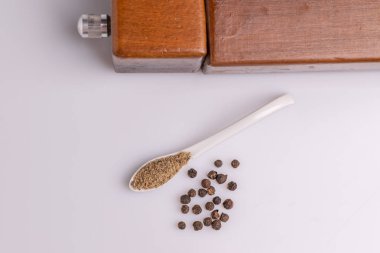 Beyaz arka plan üzerinde izole beyaz bir kaşık siyah ve beyaz biber. Latince adı 