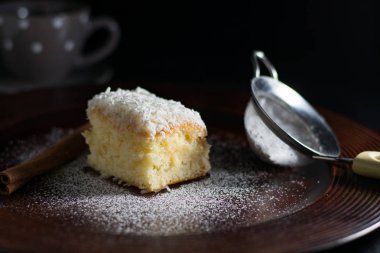 siyah arka plan üzerinde hindistan cevizi sünger kek, yüzeyde ve bir elek te şekerleme şekeri