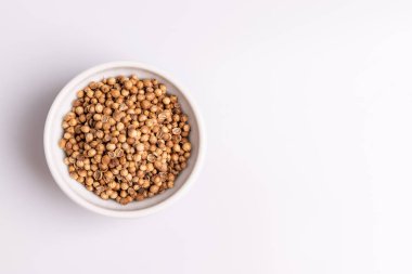 Beyaz arka planda izole beyaz seramik kase kişniş tohumları üst görünümü