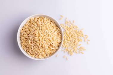 Beyaz seramik bolw Orzo makarna, beyaz arka plan üzerinde izole. Pirinç taneleri şeklinde İtalyan orzo makarna