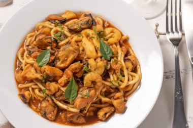 Beyaz ahşap arka plan üzerinde beyaz tabakta deniz meyvesi ile Makarna