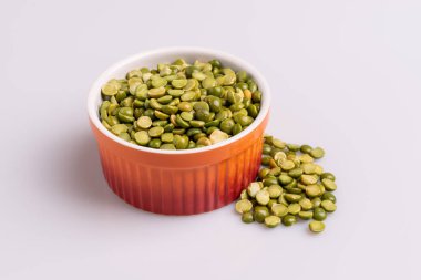 Bölünmüş bir portakal ramekin içinde pişmiş pişmemiş bezelye, beyaz arka plan üzerinde izole