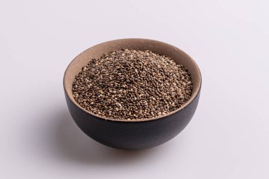 Topraklı chia tohumu (Salvia hispanica) kahverengi seramik bir kapta, beyaz arka plan üzerinde izole