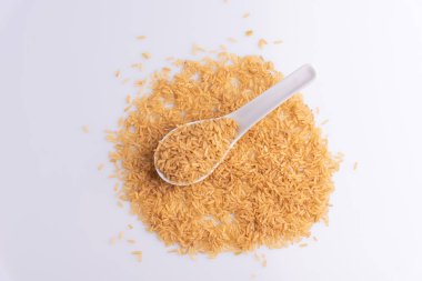 Beyaz arka plan üzerinde beyaz bir kaşık çiğ kahverengi pirinç