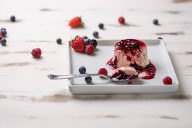Berry soslu lezzetli İtalyan tatlı panna cotta, beyaz ahşap backgroun taze çilek