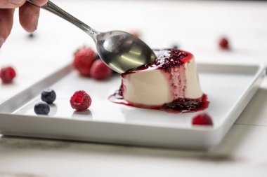 Berry soslu lezzetli İtalyan tatlı panna cotta, beyaz ahşap backgroun taze çilek