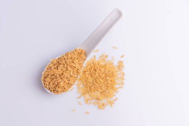 Beyaz arka plan üzerinde beyaz bir kaşık Ham Kahverengi Pirinç Üst görünümü