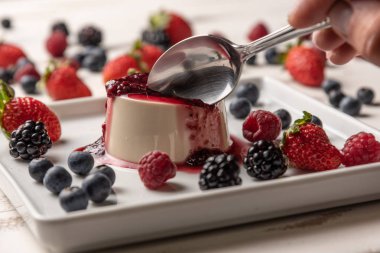 Berry soslu lezzetli İtalyan tatlı panna cotta, beyaz ahşap backgroun taze çilek